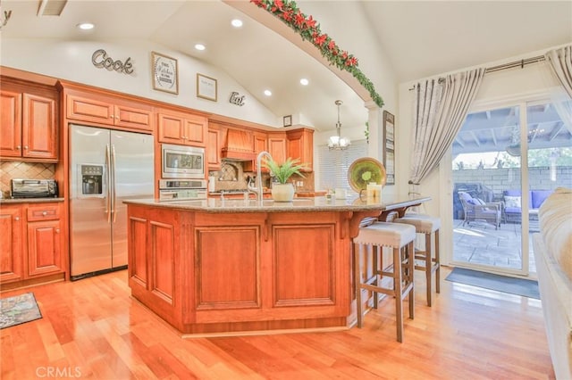 kitchen featuring a chandelier, hanging light fixtures, light hardwood / wood-style flooring, a kitchen breakfast bar, and stainless steel appliances