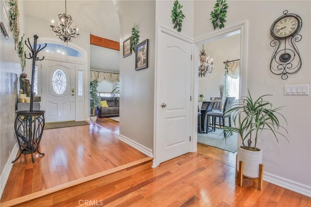 entryway featuring hardwood / wood-style floors, a towering ceiling, and a chandelier