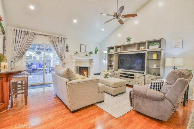 living room with light hardwood / wood-style flooring, high vaulted ceiling, and ceiling fan