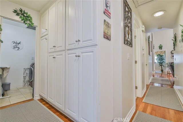 hallway with washer / clothes dryer and light hardwood / wood-style flooring