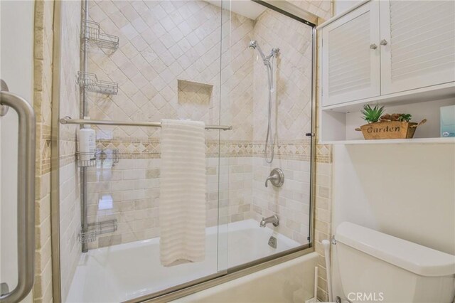 bathroom featuring enclosed tub / shower combo and toilet