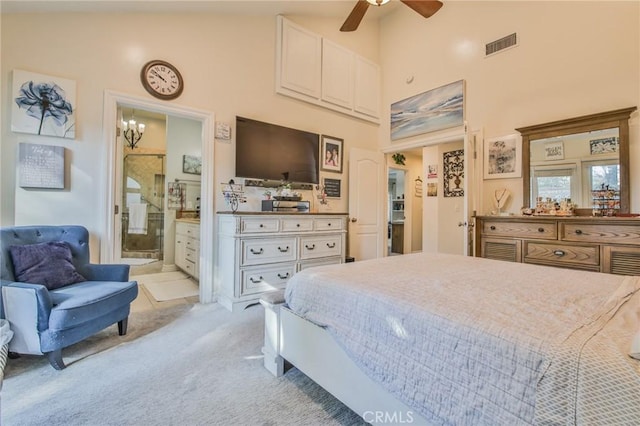 bedroom with ceiling fan, a towering ceiling, light colored carpet, and ensuite bath