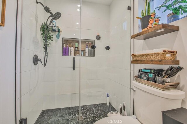 bathroom with a shower with door and toilet