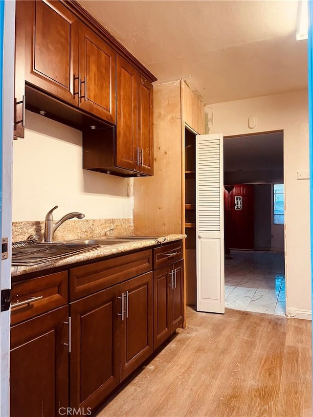 kitchen featuring sink, light stone countertops, and light wood-type flooring