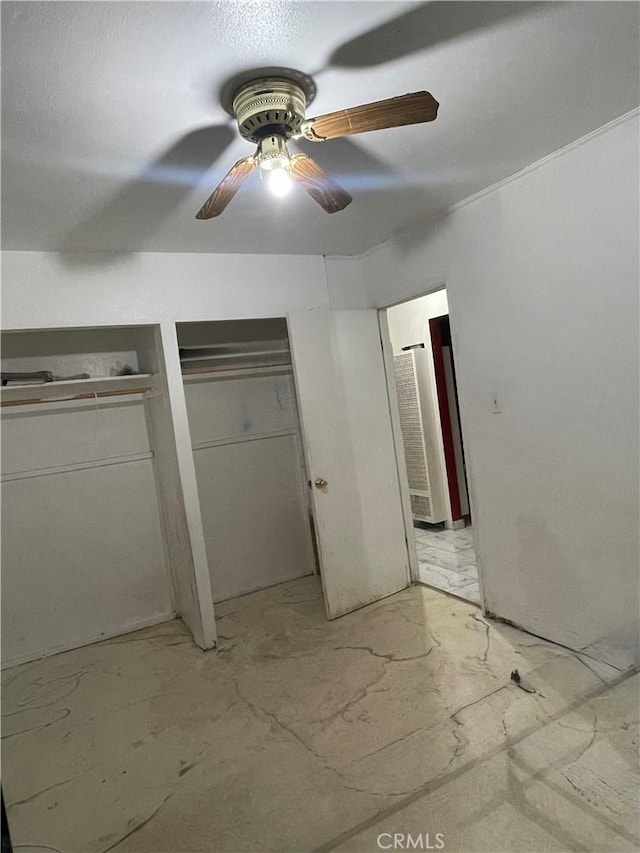 unfurnished bedroom with multiple closets and ceiling fan