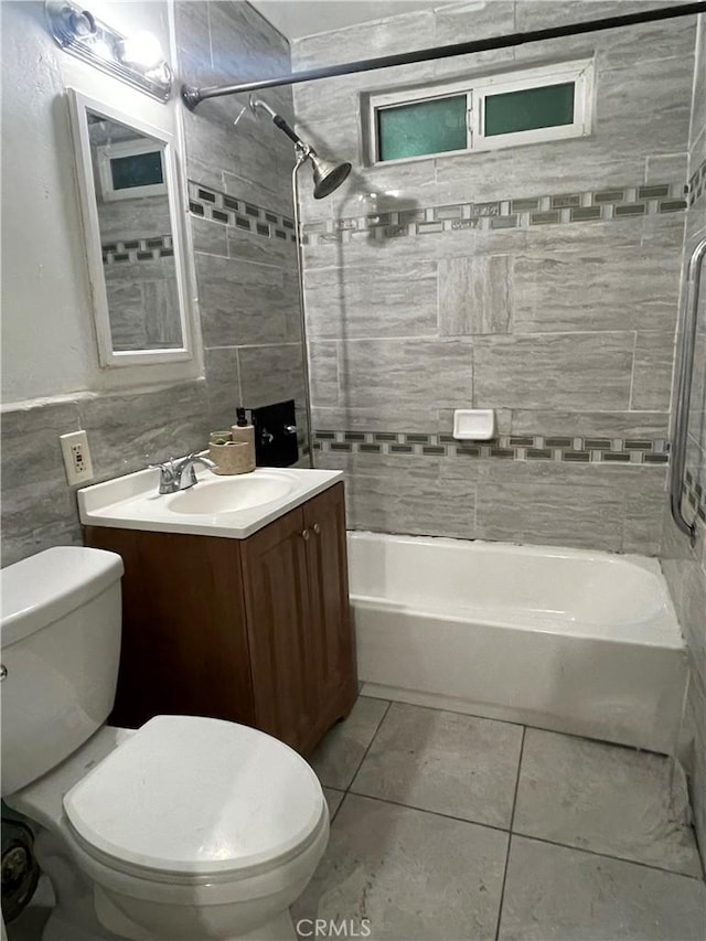 full bathroom featuring tile patterned floors, toilet, tile walls, vanity, and tiled shower / bath combo