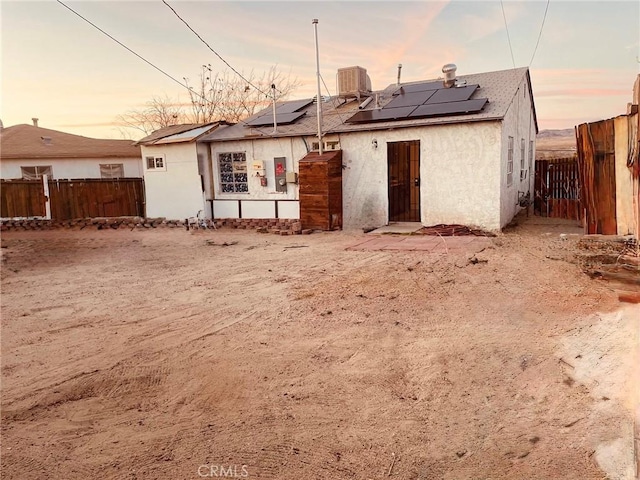 back house at dusk with cooling unit and solar panels