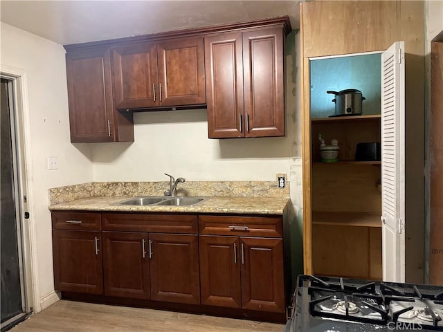 kitchen with sink, range with gas stovetop, and light wood-type flooring