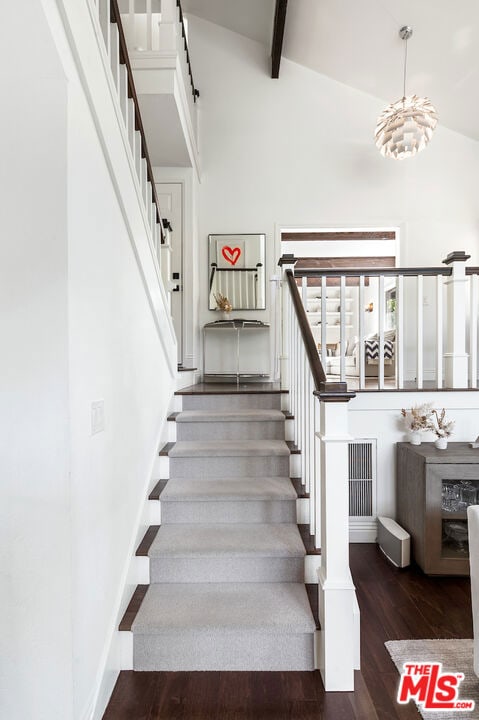 stairway featuring beamed ceiling, wood-type flooring, and high vaulted ceiling