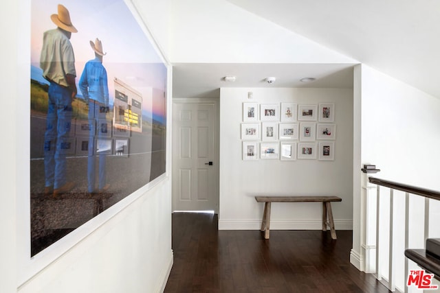 corridor with dark hardwood / wood-style flooring and vaulted ceiling