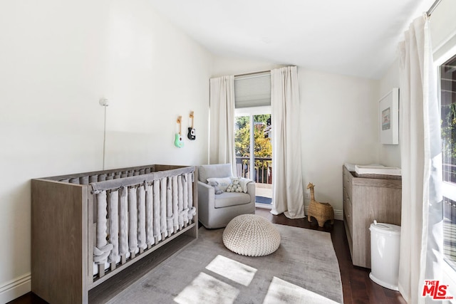 bedroom with a baseboard heating unit, a nursery area, lofted ceiling, and dark wood-type flooring