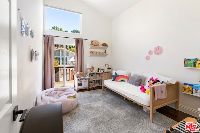 bedroom with hardwood / wood-style flooring, access to exterior, and high vaulted ceiling