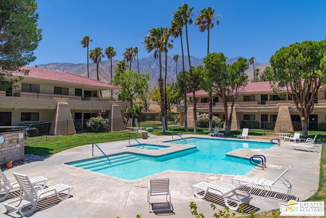 view of swimming pool featuring a community hot tub, a mountain view, and a patio area