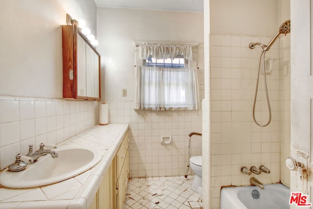 full bathroom with tiled shower / bath, tile walls, tile patterned flooring, vanity, and toilet