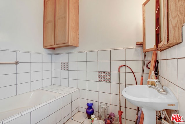 bathroom featuring tile walls, tiled tub, and sink