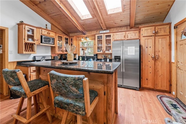 kitchen featuring light hardwood / wood-style flooring, wooden ceiling, dark stone counters, stainless steel appliances, and vaulted ceiling with skylight