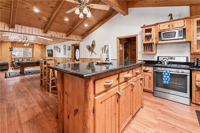 kitchen featuring appliances with stainless steel finishes, lofted ceiling with beams, a kitchen island, and light hardwood / wood-style flooring