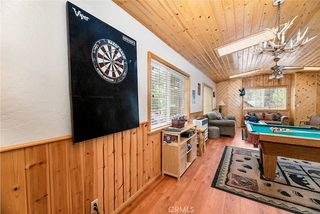 rec room with lofted ceiling with skylight, hardwood / wood-style floors, wooden ceiling, and wood walls