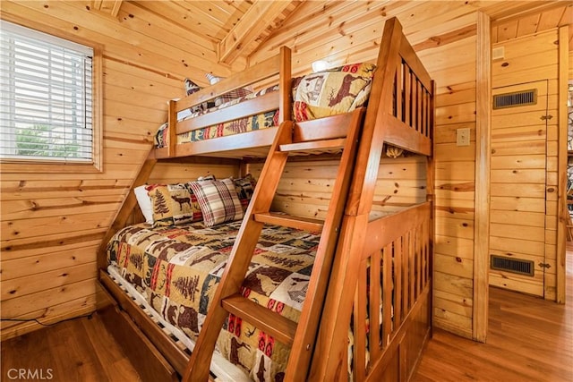 bedroom with hardwood / wood-style flooring and wooden walls