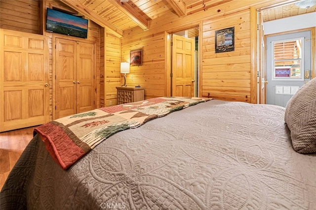 bedroom with hardwood / wood-style floors, lofted ceiling with beams, wooden ceiling, and wood walls