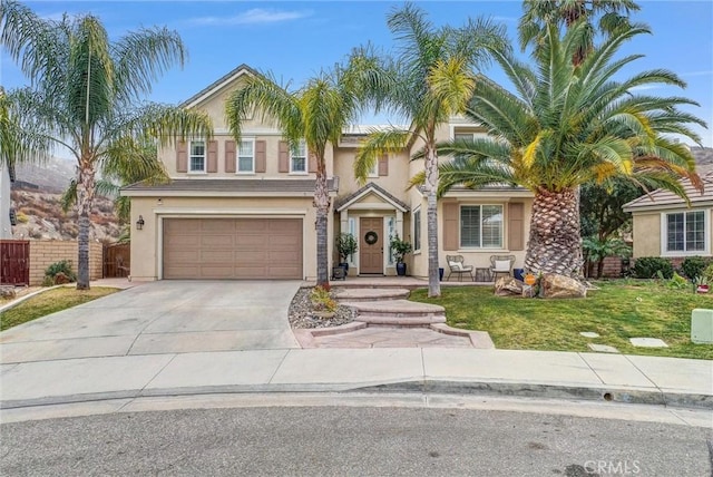 view of front of property featuring driveway, a garage, stucco siding, fence, and a front yard