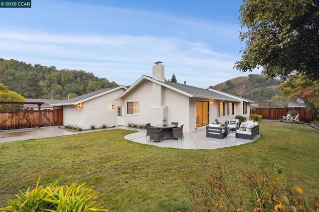 back of house with an outdoor living space, a lawn, and a patio area