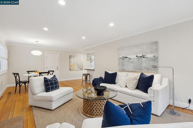 living room featuring crown molding, a healthy amount of sunlight, and light wood-type flooring