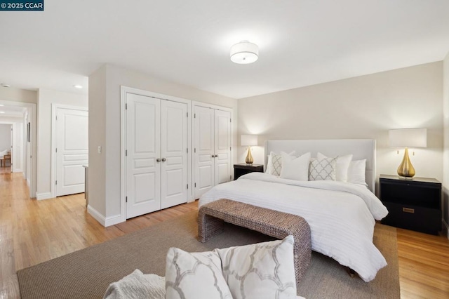 bedroom featuring light hardwood / wood-style floors and multiple closets