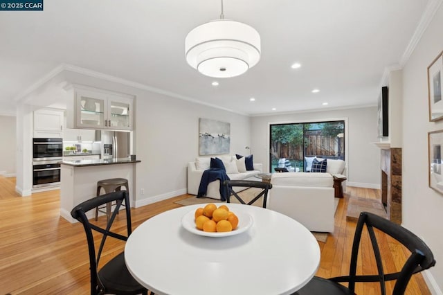 dining space with ornamental molding and light wood-type flooring