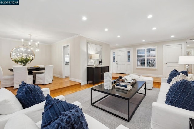 living room with ornamental molding, light hardwood / wood-style floors, and a notable chandelier