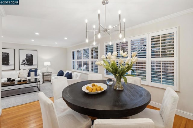 dining area featuring crown molding, an inviting chandelier, and light wood-type flooring