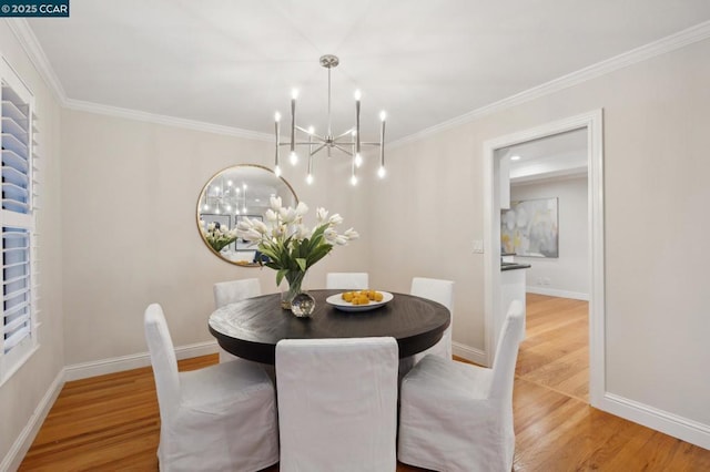 dining space featuring crown molding, an inviting chandelier, and light hardwood / wood-style floors