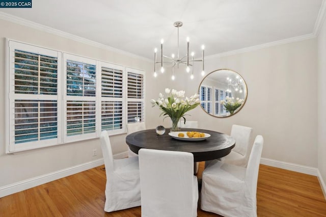 dining room with wood-type flooring, ornamental molding, and a notable chandelier