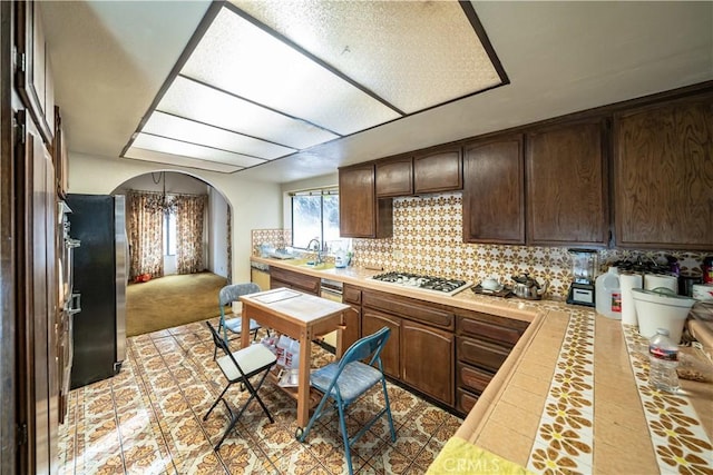 kitchen featuring stainless steel refrigerator, sink, decorative backsplash, dark brown cabinets, and white gas cooktop