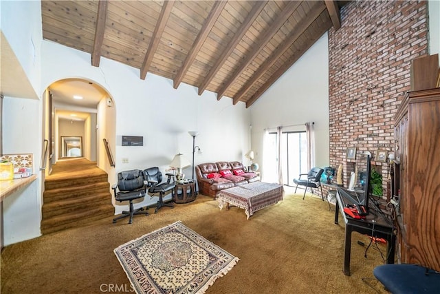 carpeted bedroom with beamed ceiling, high vaulted ceiling, wood ceiling, and a brick fireplace