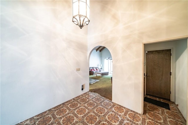 hall featuring a towering ceiling, a chandelier, and carpet flooring