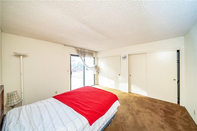 carpeted bedroom with two closets, access to exterior, and a textured ceiling