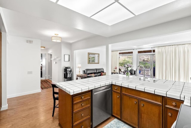 kitchen with sink, tile countertops, stainless steel dishwasher, and kitchen peninsula