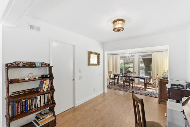 office space featuring a chandelier and light wood-type flooring