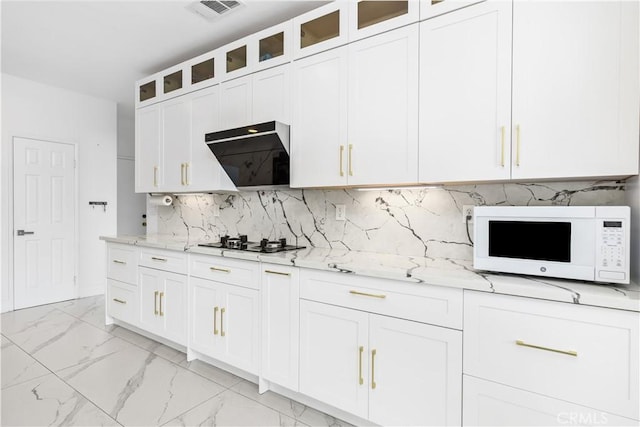 kitchen with wall chimney exhaust hood, gas stovetop, light stone counters, white cabinetry, and decorative backsplash