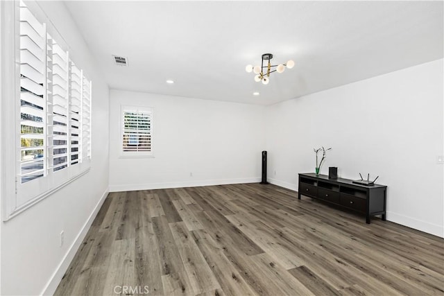 unfurnished room featuring an inviting chandelier and dark hardwood / wood-style flooring