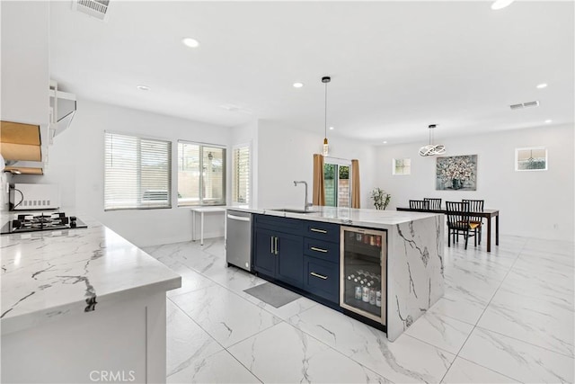 kitchen with decorative light fixtures, white cabinetry, sink, blue cabinetry, and a center island with sink