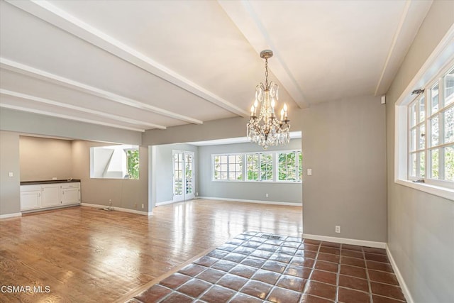 spare room featuring dark hardwood / wood-style floors, beam ceiling, and a notable chandelier