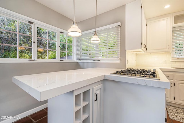 kitchen featuring stainless steel gas stovetop, tasteful backsplash, white cabinets, hanging light fixtures, and kitchen peninsula