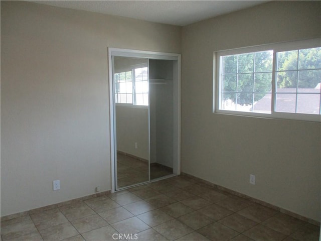 unfurnished bedroom featuring multiple windows, tile patterned floors, and a closet