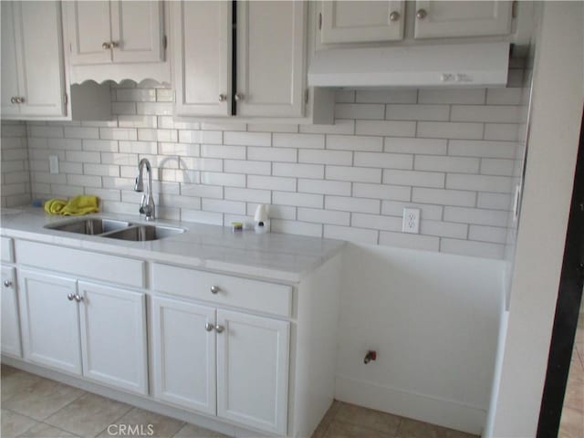 kitchen featuring sink, light stone countertops, white cabinets, decorative backsplash, and exhaust hood