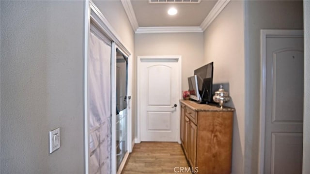 hallway with ornamental molding and light hardwood / wood-style flooring