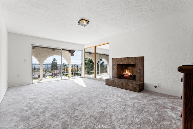 unfurnished living room with carpet floors, a fireplace, and a textured ceiling