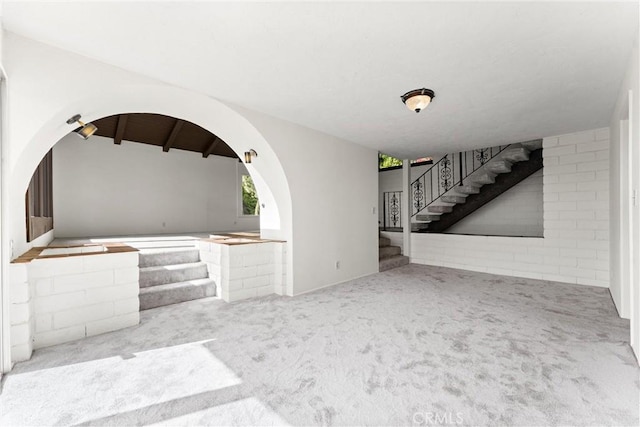 unfurnished living room with light colored carpet and lofted ceiling with beams