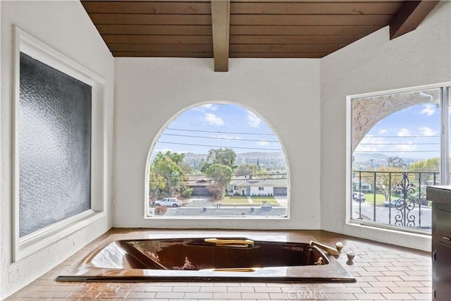 bathroom with vaulted ceiling with beams, a tub to relax in, and wooden ceiling